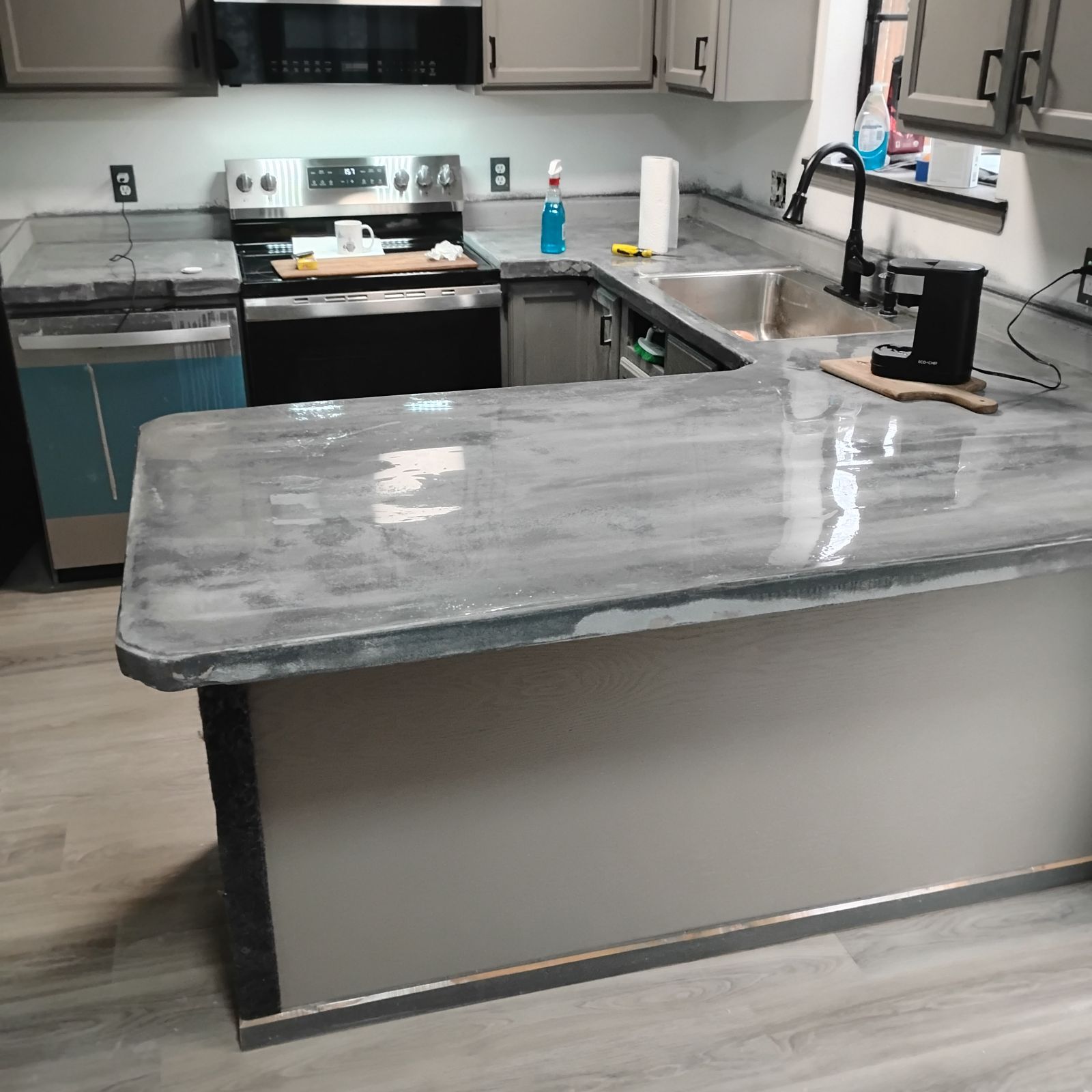 Kitchen peninsula and perimeter countertops finished in gray microcement with a polished sheen