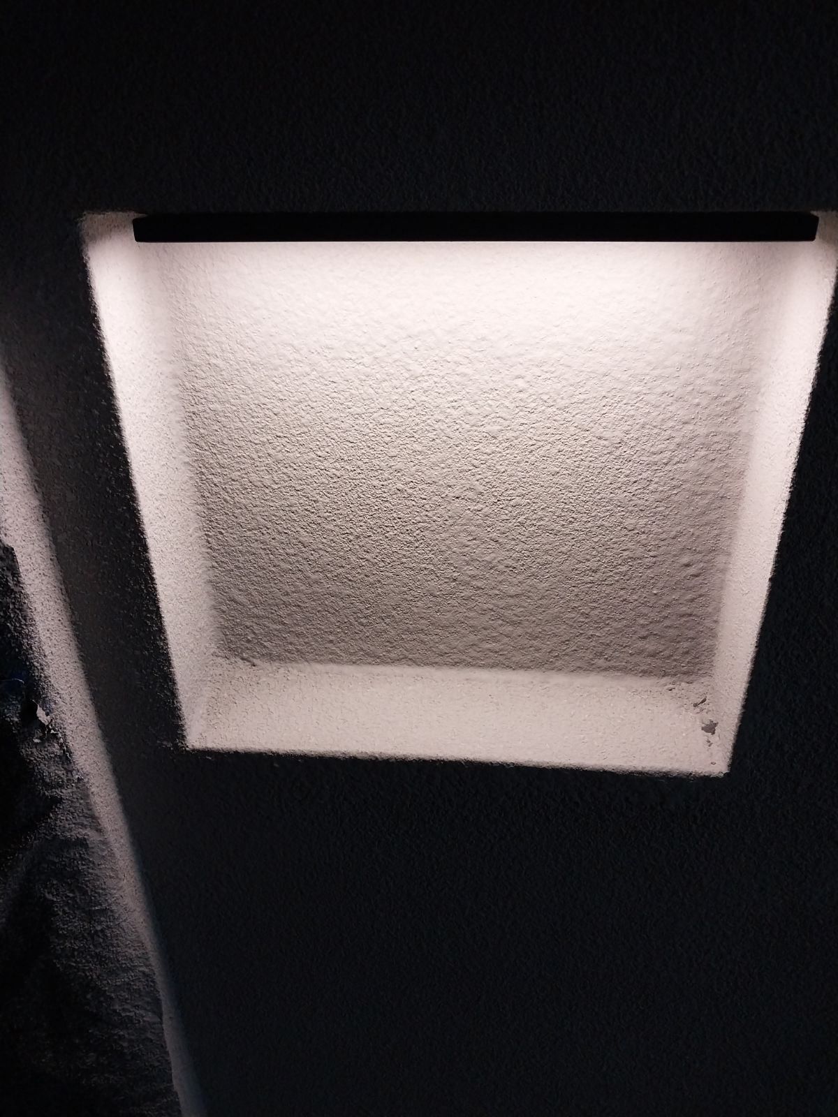Recessed wall shelf finished in microcement, lit by a concealed LED strip