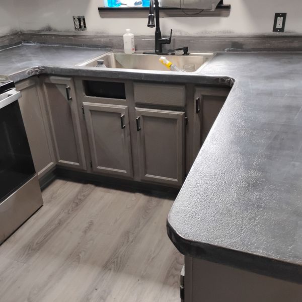 U-shaped kitchen countertops coated in dark gray microcement