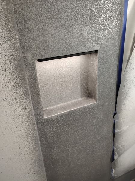 Textured microcement surface around a recessed wall shelf